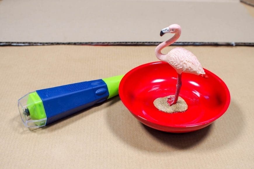 A red bowl with a pink plastic flamingo glued in the center
