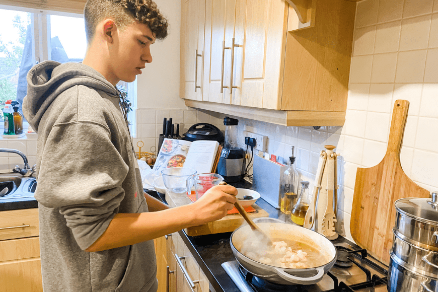 Teen in the kitchen cooking a King Prawn and Spicy Maple Curry 