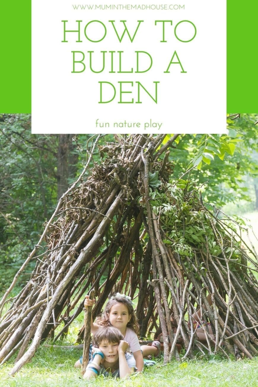 Two children laid on the ground , one with a stick under a tent made of sticks like a den 