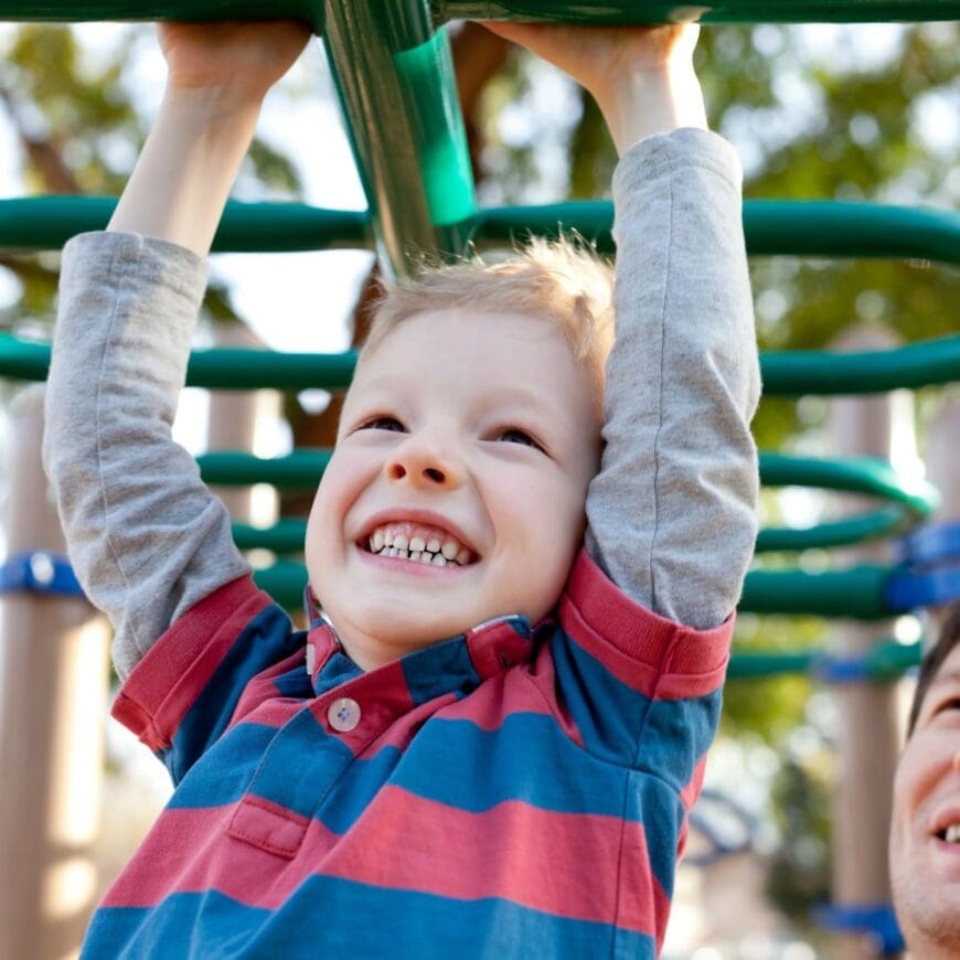 Child learning to use monkey bars at a playground